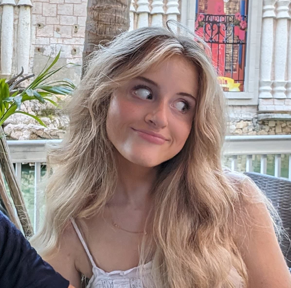 On a shaded veranda overlooking a quiet courtyard, warm light drifts through palms and old stone, catching in loose hair and half-finished thoughts. The moment feels like a pause between conversations—laughter just passed, inspiration about to arrive—where the air hums with possibility and the world seems gently amused. It’s an easy, playful breath of an afternoon, the kind that invites sketches on napkins and dreams to wander.