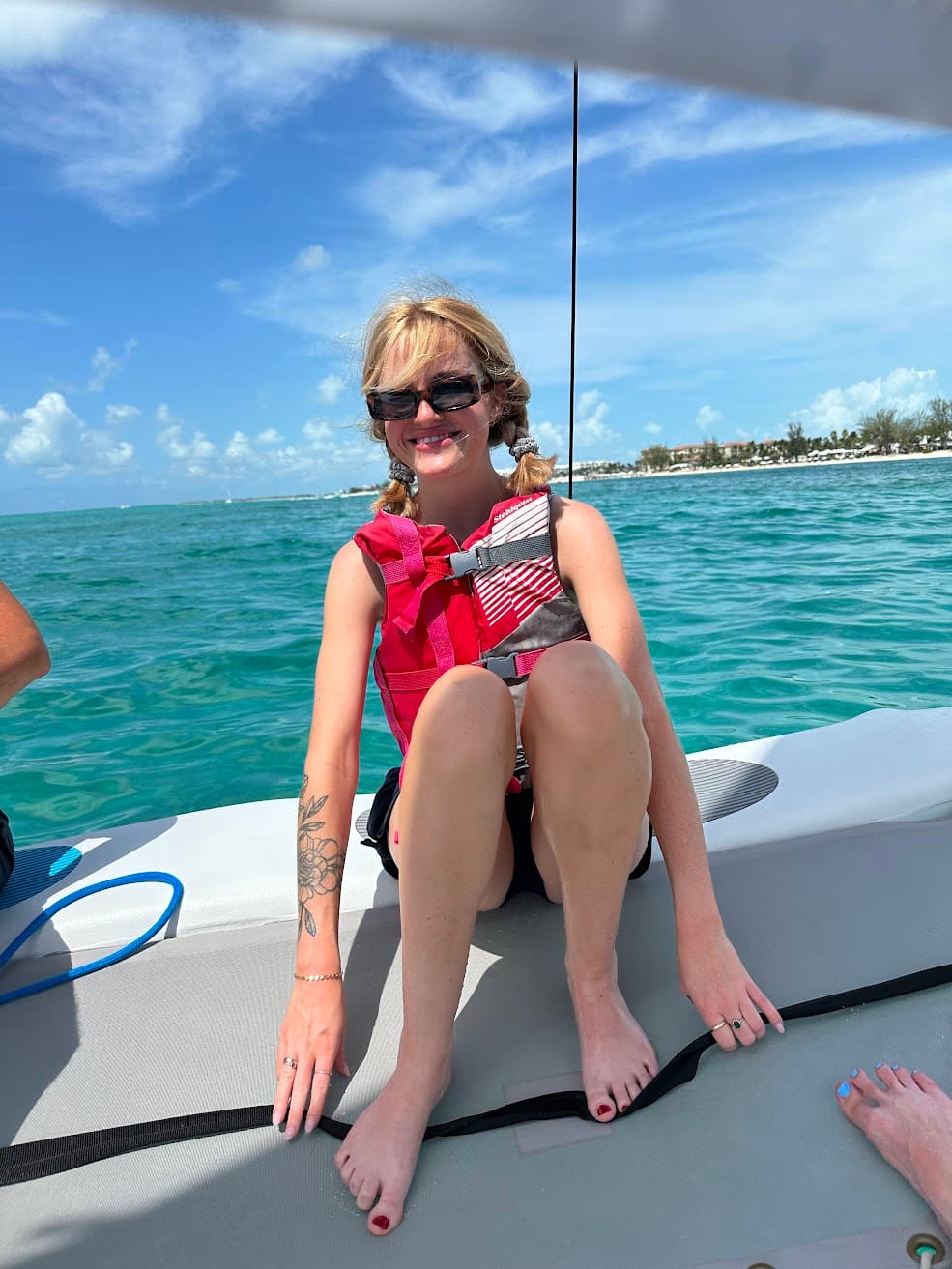 On a small boat floating over clear turquoise water, the afternoon feels unhurried, sun-warmed, and salt-kissed, the shoreline drifting quietly in the distance. A pause between adventures unfolds here—bare feet on the deck, a life vest loosened, laughter lingering in the breeze as the sea gently rocks everything into stillness. The mood is light and open, a moment of freedom where the horizon seems wide enough to hold every possibility.